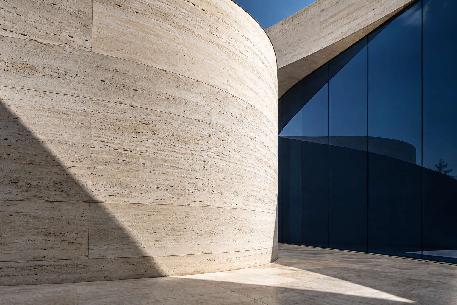 Sunlit stone curves beside deep blue architectural glass